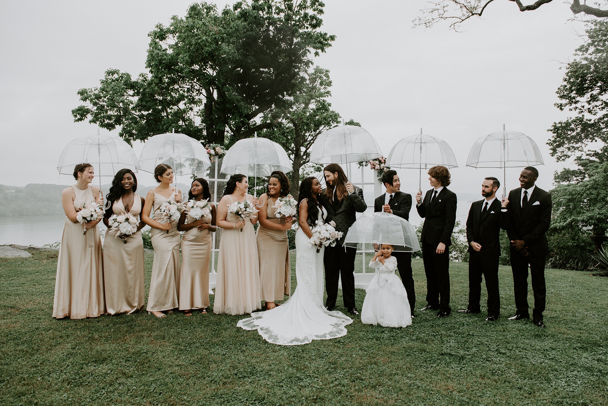 A wedding party standing together with the river behind them.